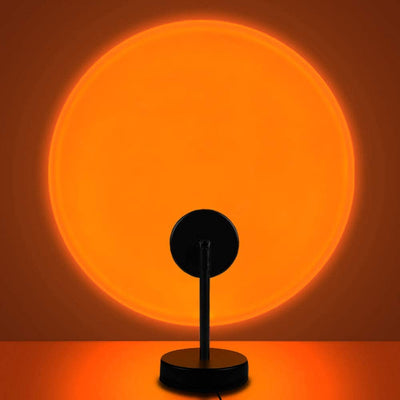 Aesthetic sunset projection lamp casting warm orange light on a wall with a black base