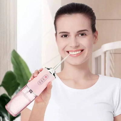 Woman using a pink waterproof dental irrigator for oral hygiene at home