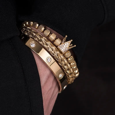 Gold tone stainless steel Roman bracelets featuring a crown charm and crystal accents on wrist