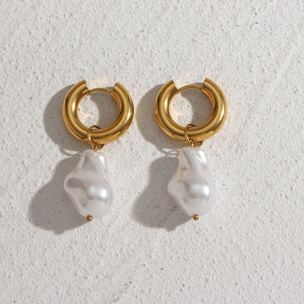 Elegant water drop earrings with gold hoop and irregular white pearl pendant on textured surface