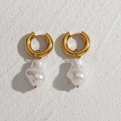 Elegant water drop earrings with gold hoop and irregular white pearl pendant on textured surface