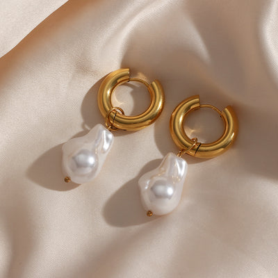 Elegant water drop earrings with gold hoops and white pearl-like drops on satin fabric