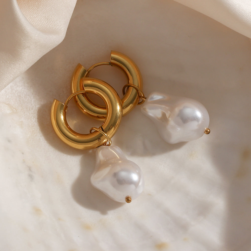 Elegant water drop earrings with gold hoop and large pearl drop design on marble surface