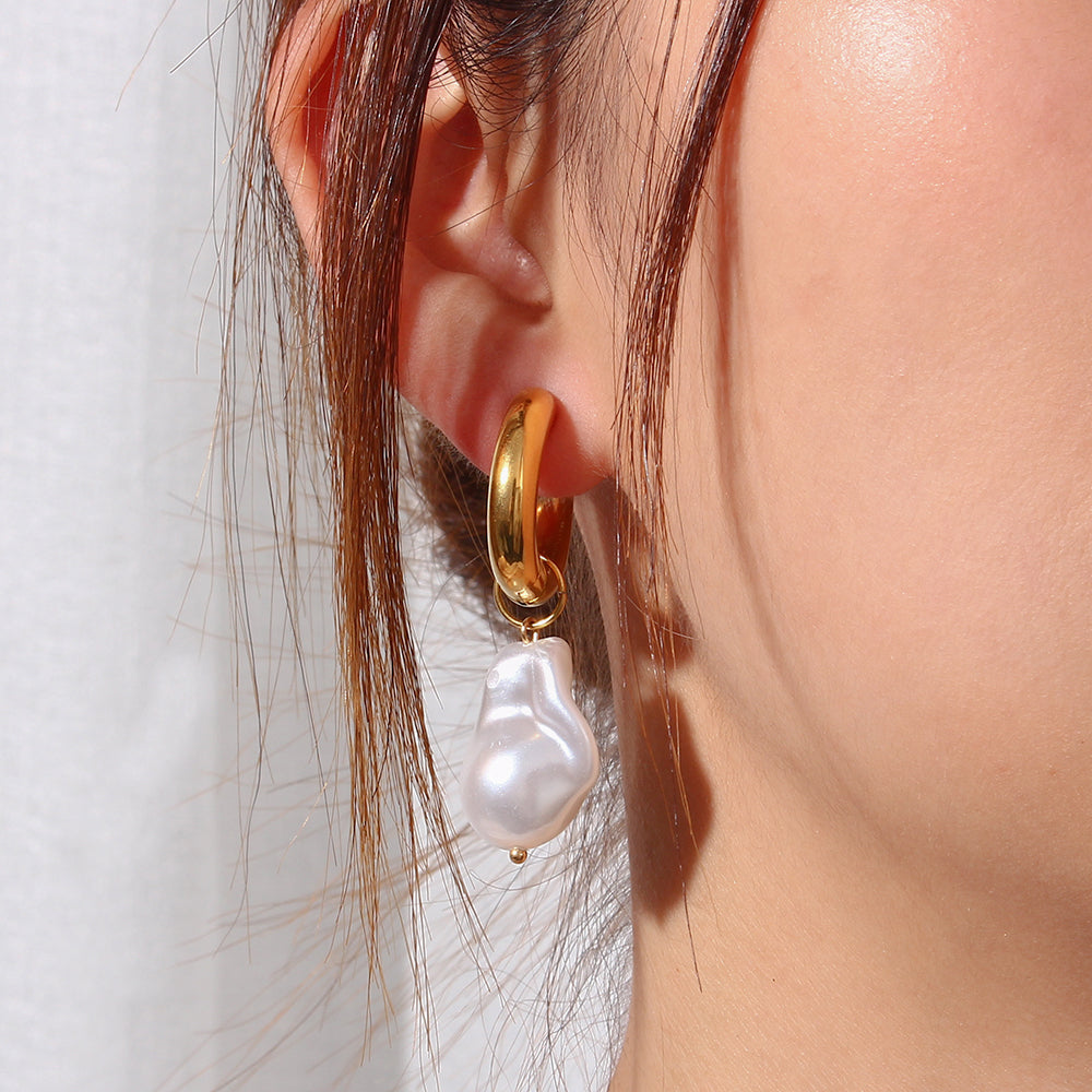 Close-up of elegant water drop earrings with gold hoop and white pearl drop on ear